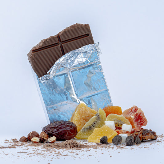 Chocolate bar, dried fruits, and nuts on a light blue background